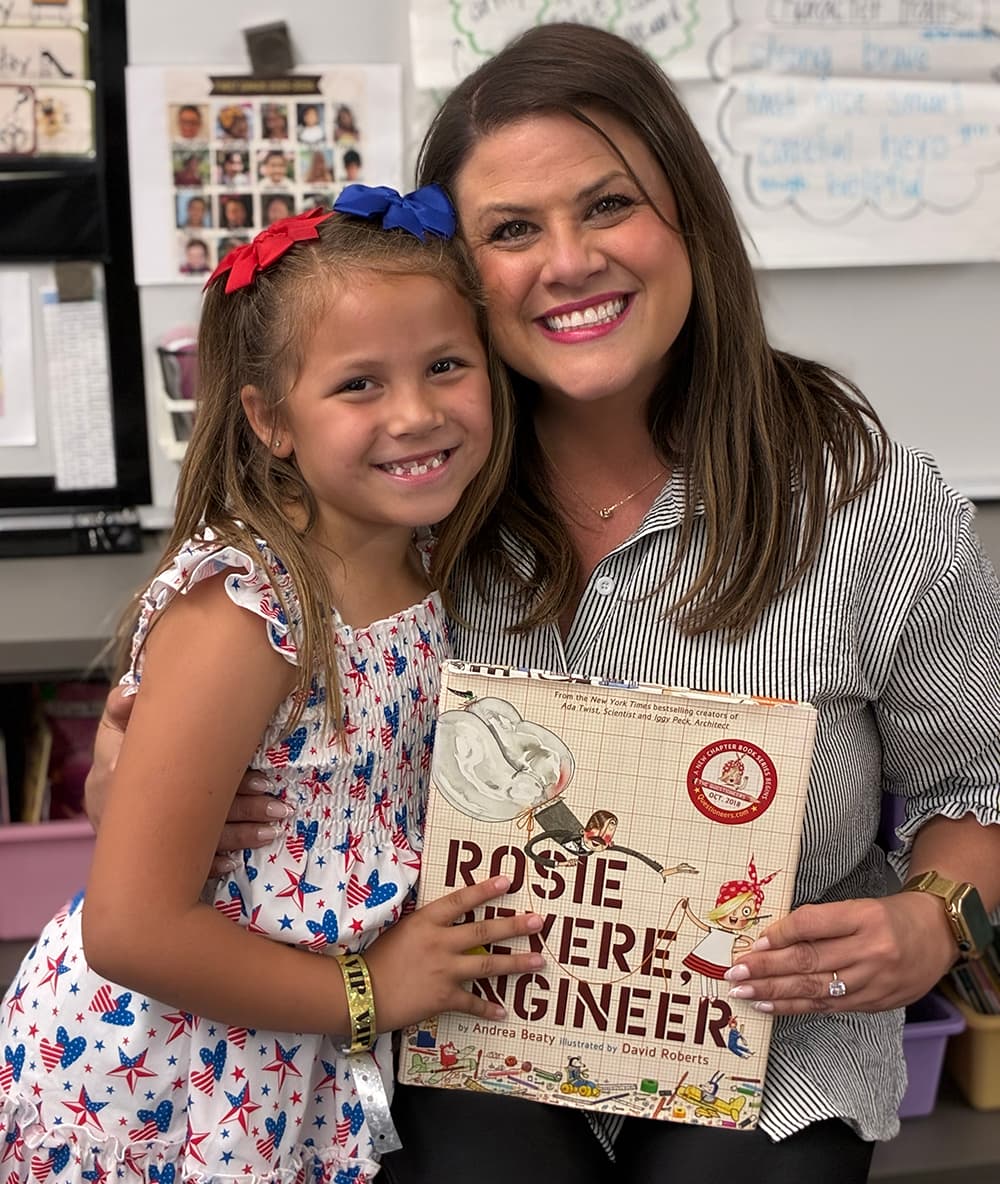 A parent and her child in the classroom holding the book she came in to read