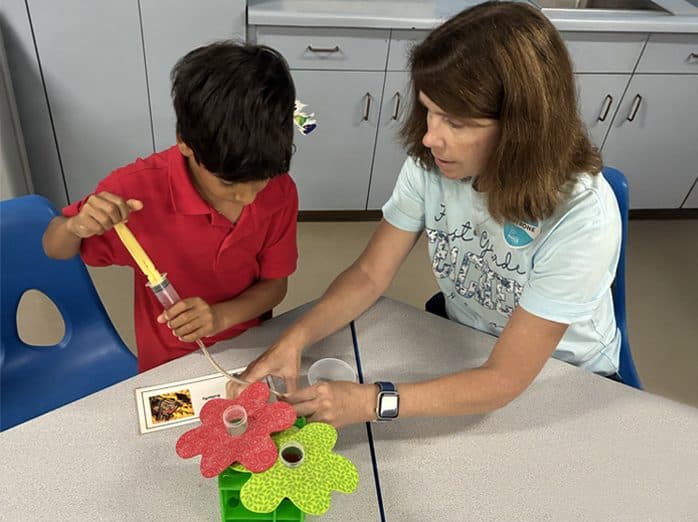 A student and teacher work together on a pollination experiment in the science lab