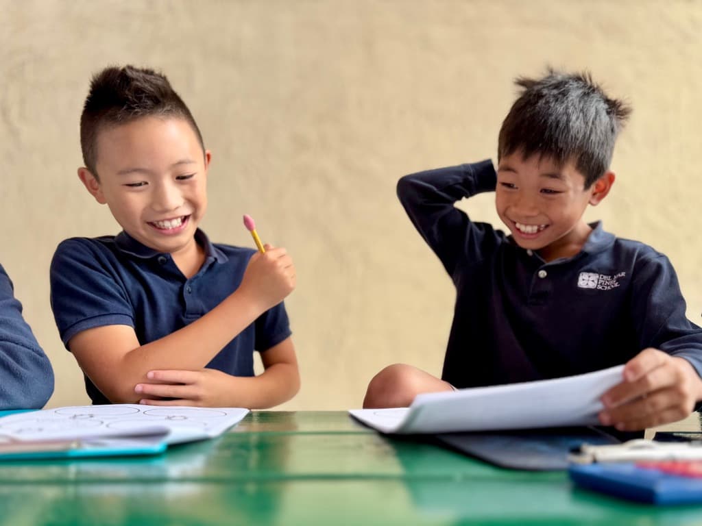 Two students laughing together over their classwork