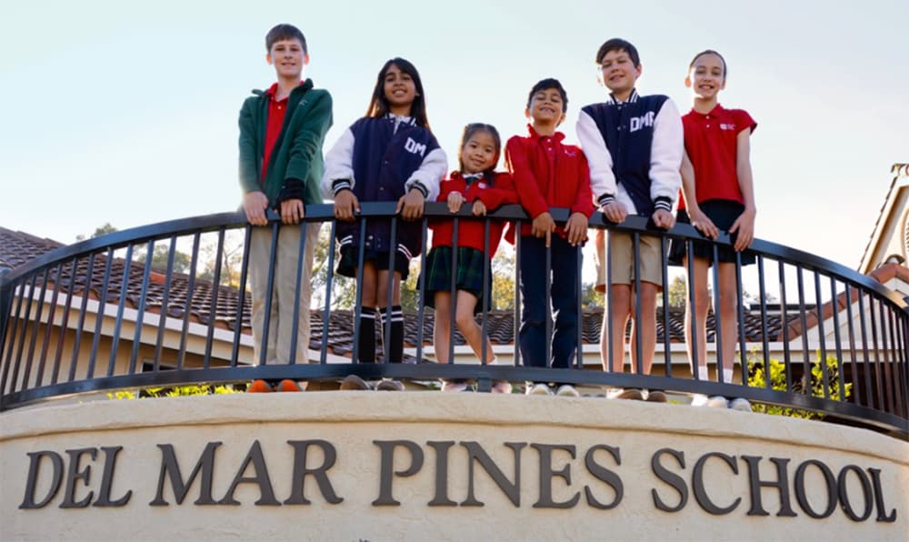 Six Del Mar Pines students in uniform standing together behind the black fence